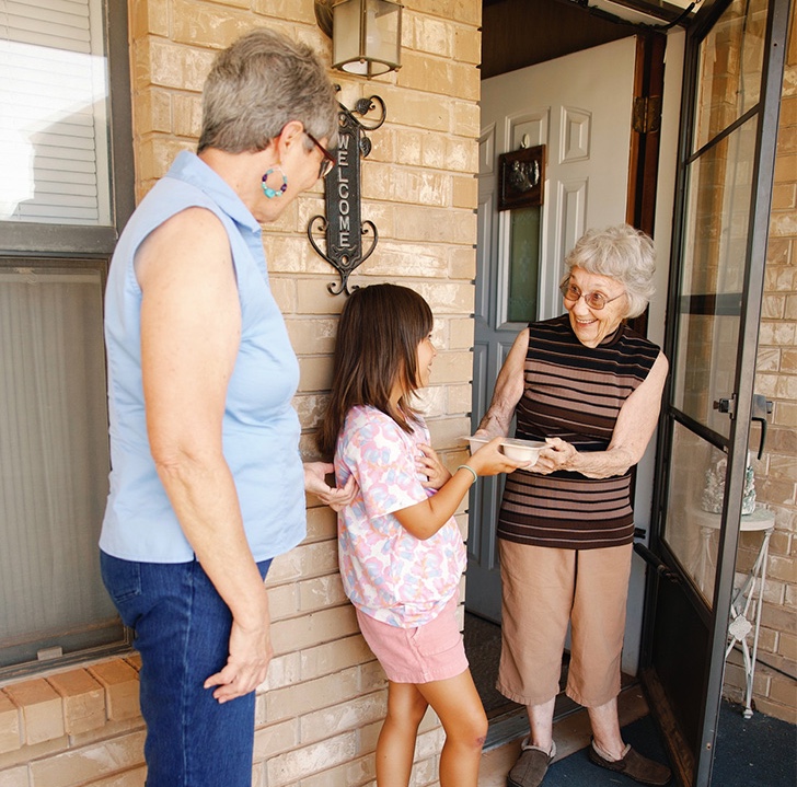 volunteers delivering to a meal recipient's door.